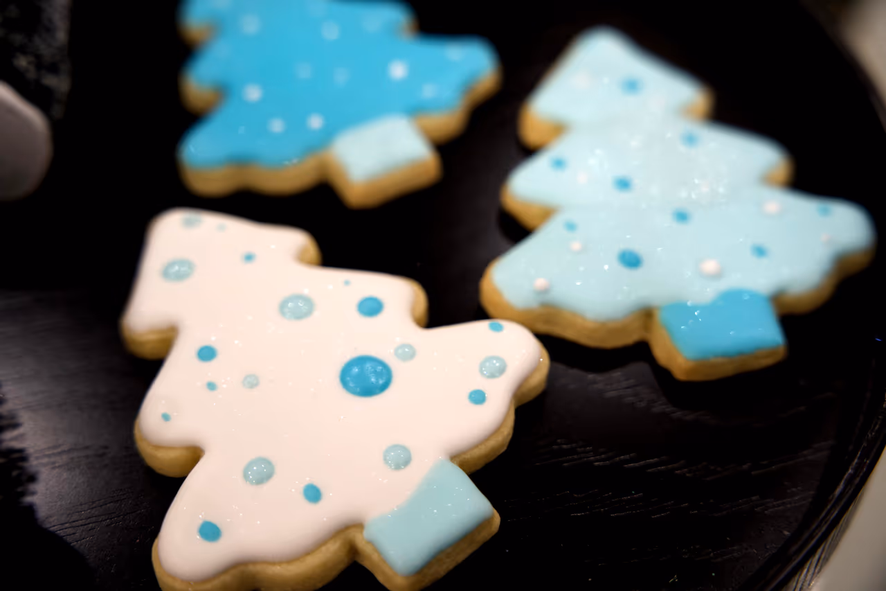 3 cookies in the shape of trees with bright blue, light blue, and white icing.