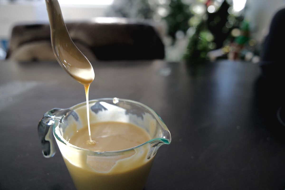 brown sauce dropping off a spoon into a measuring cup. 