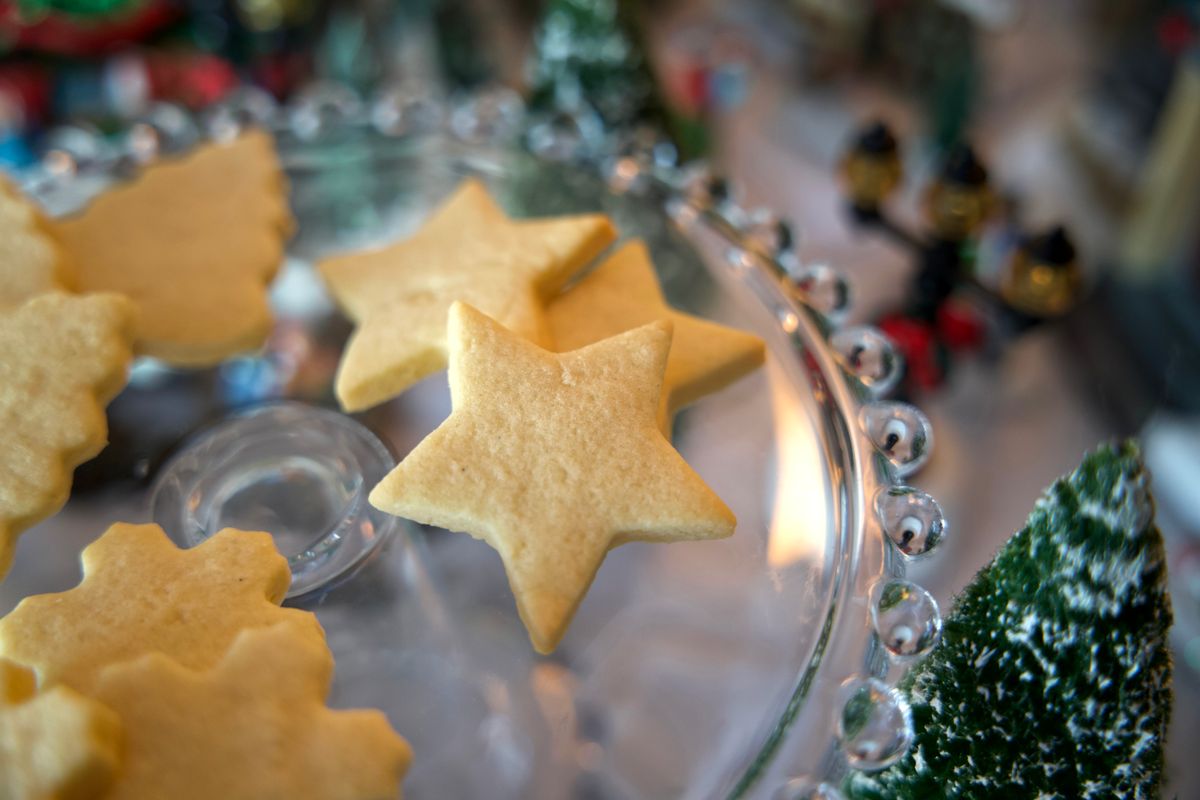 Star shaped, bare sugar cookie on a plate in front of holiday scene.