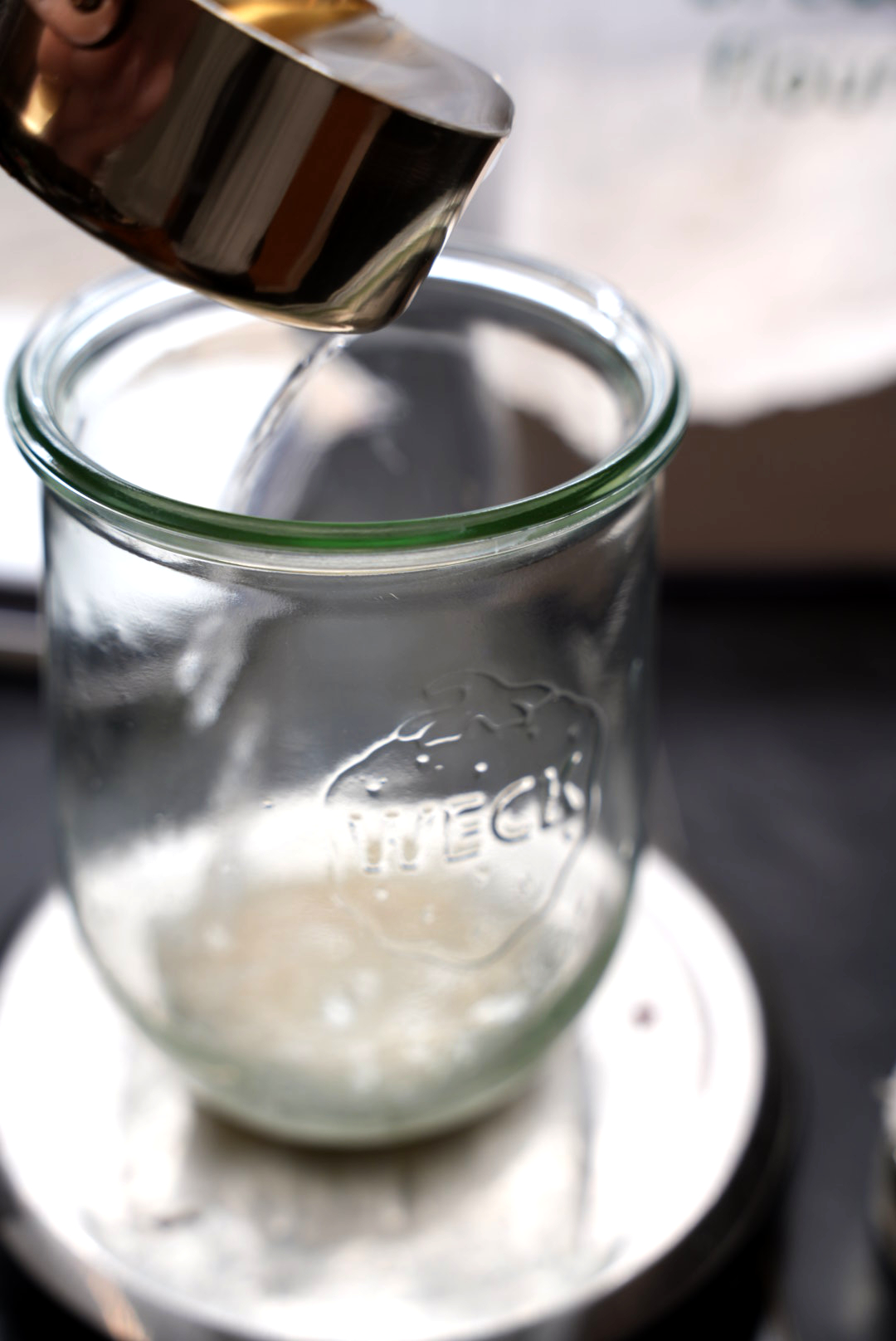 Water being poured into sour dough starter. 