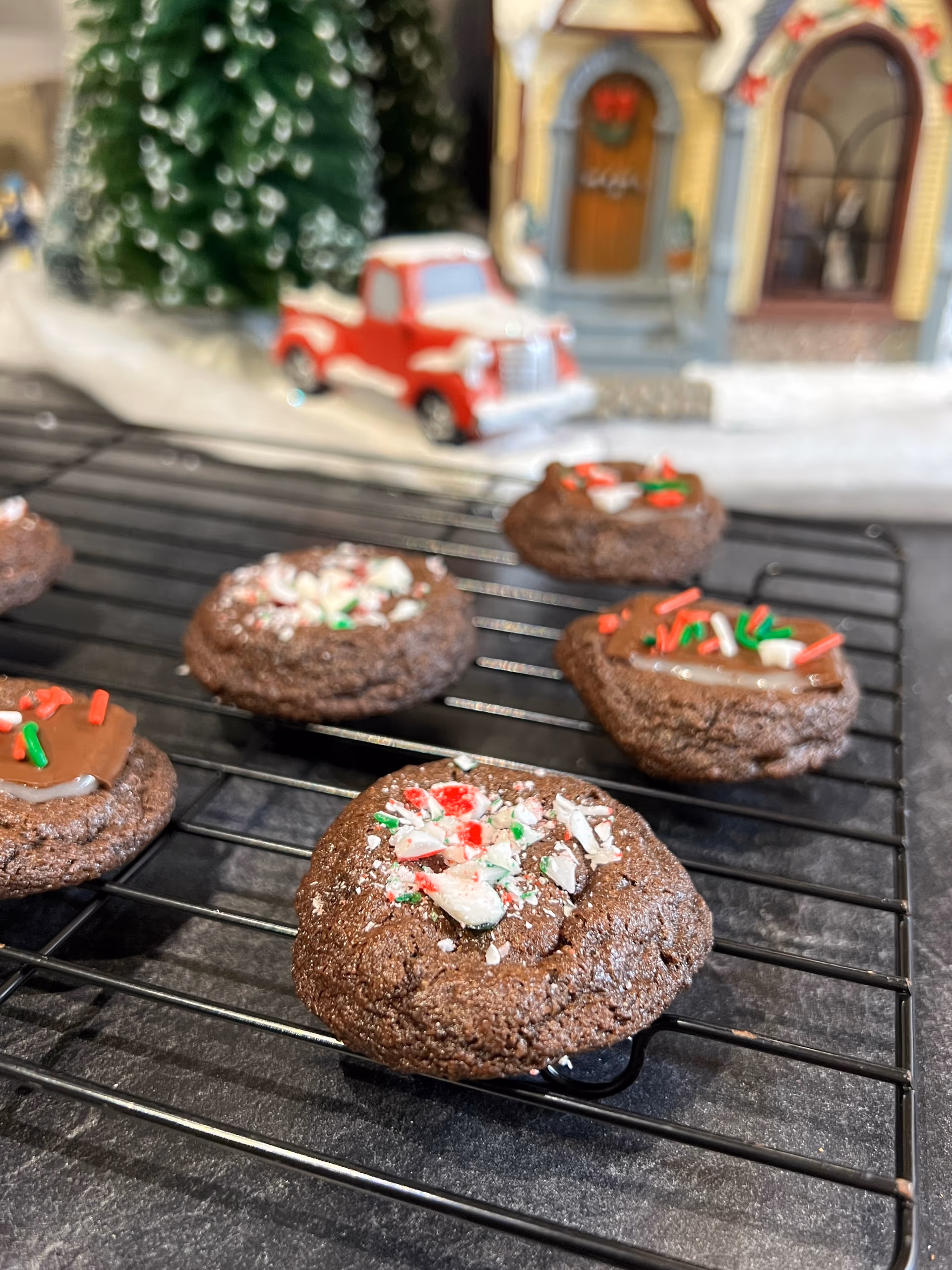 candy cane sprinkles on chocolate cookies in front of wintery scene.