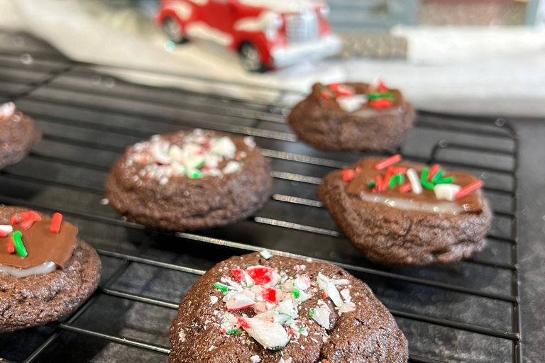 candy cane sprinkles on chocolate cookies in front of wintery scene. 